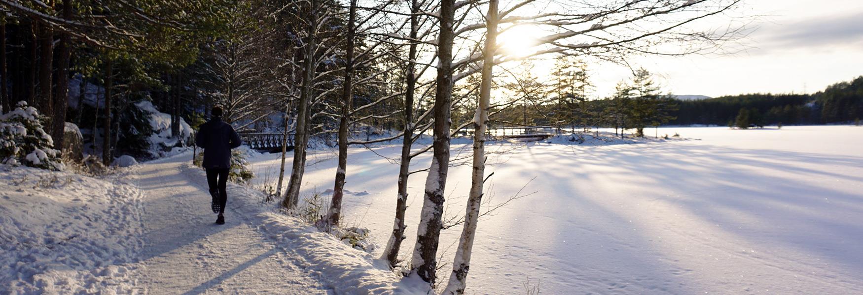 man jogging along a snow-covered body of water in winter