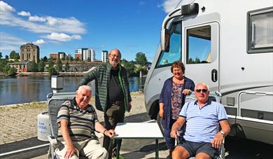 a group of elderly people are sitting next to the motorhome by the motorhome parking in Skien