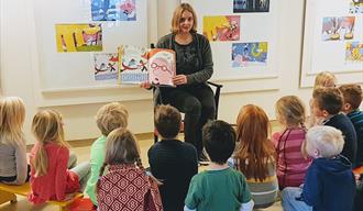 lady reading book to children at library