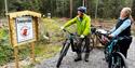 two cyclists looking at signs for the "adventure trail" at Drangedal
