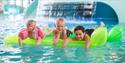 3 children lying on an air mattress in the pool of the bathing park