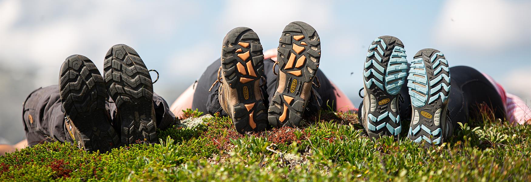 3 hikers lie on the ground and show their shoe soles