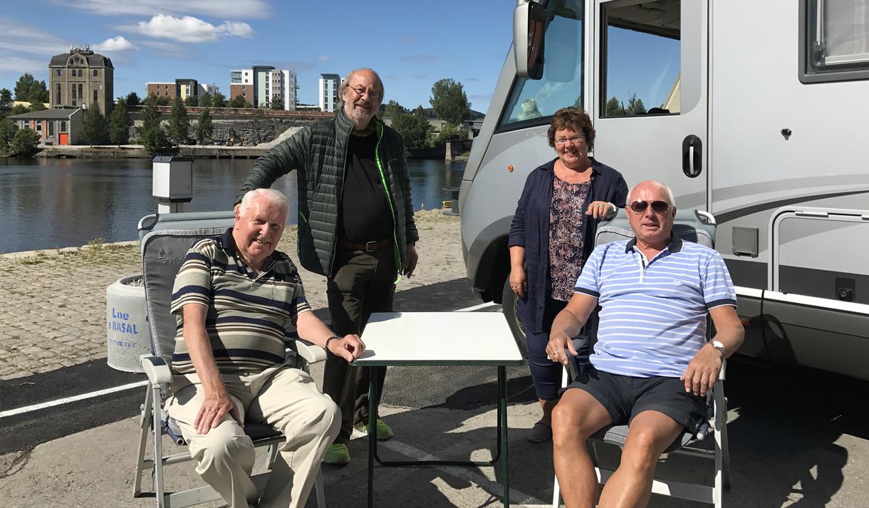 a group of elderly people are sitting next to the motorhome by the motorhome parking in Skien