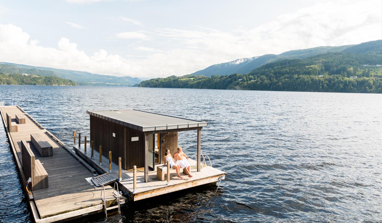couple sits on a bench at the floating sauna Dugg Sauna in Notodden