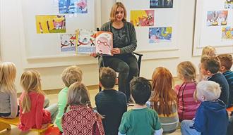 lady reading book to children at library