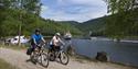 couple is bicycling along the Telemark Canal with MS Victoria in the background