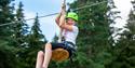 girl rides a zipline in the climbing park in Skien leisure park