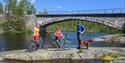 cyclists take a break on a rock by the river along the cycle path "old Treungenbanen"