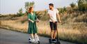 young couple vacation having fun driving electric scooter road countryside